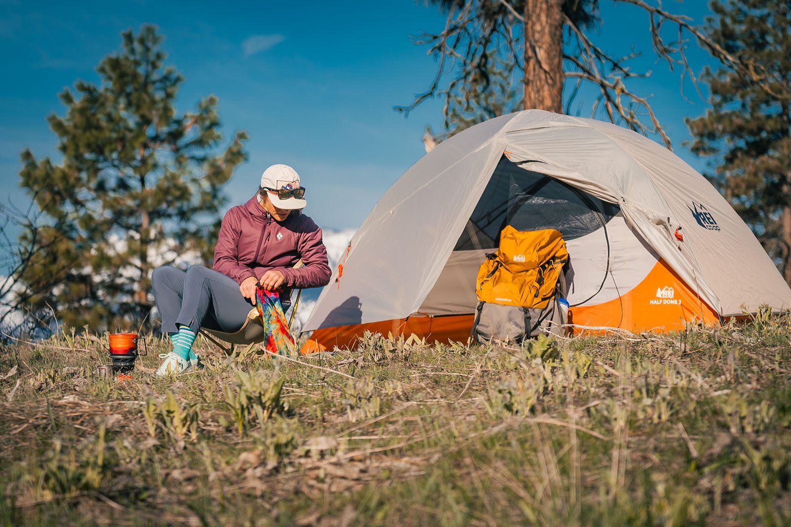 Backpacker sitting in chair next to REI Half Dome 2 tent