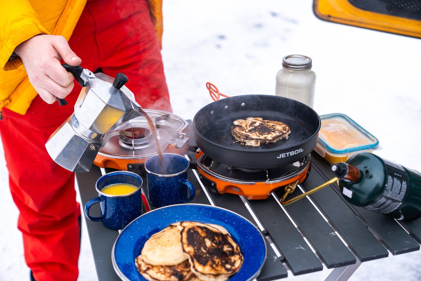Cooking pancakes and pouring coffee next to Jetboil Genesis Basecamp System camping stove
