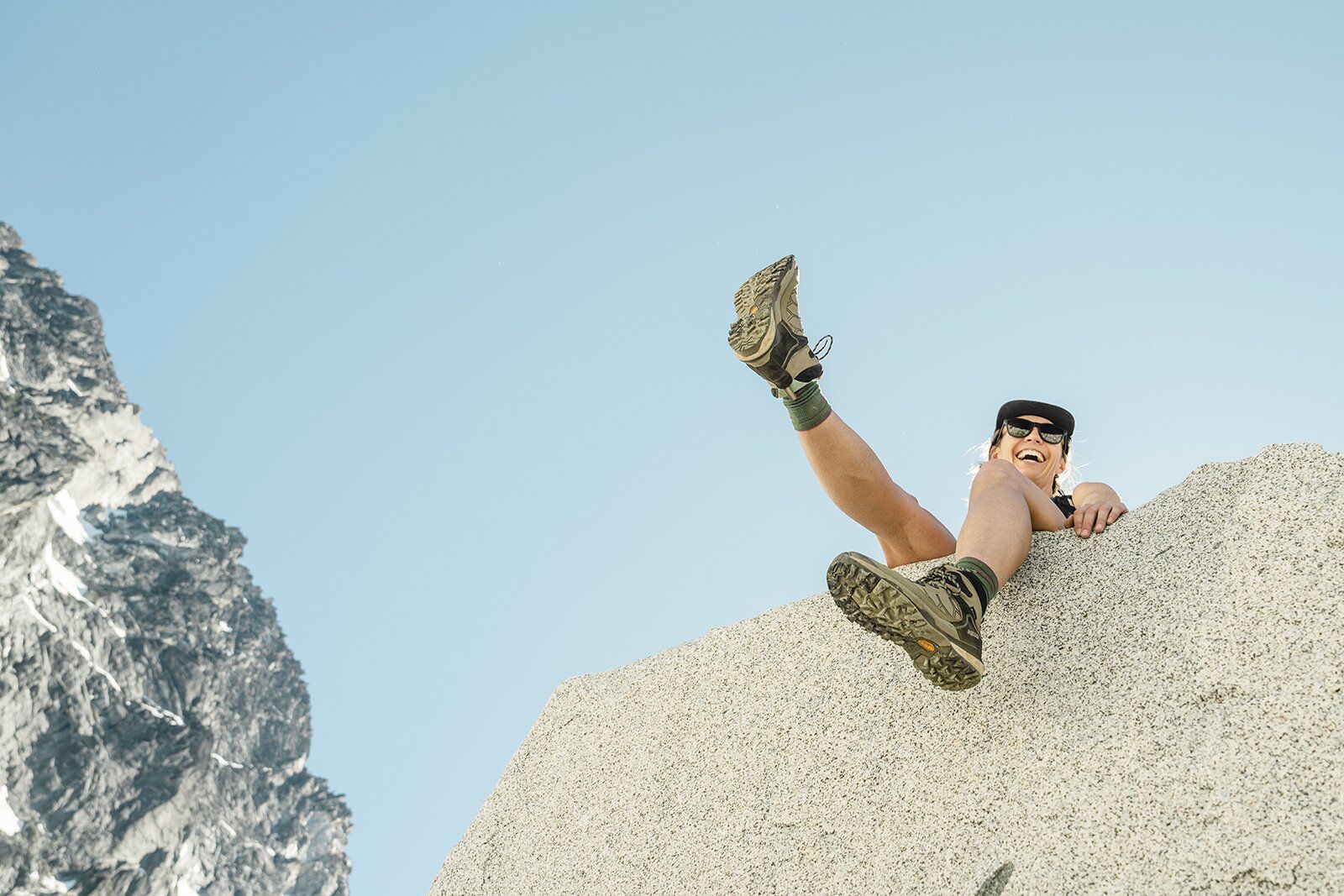 Dangling feet from mountain boulder wearing hiking boots