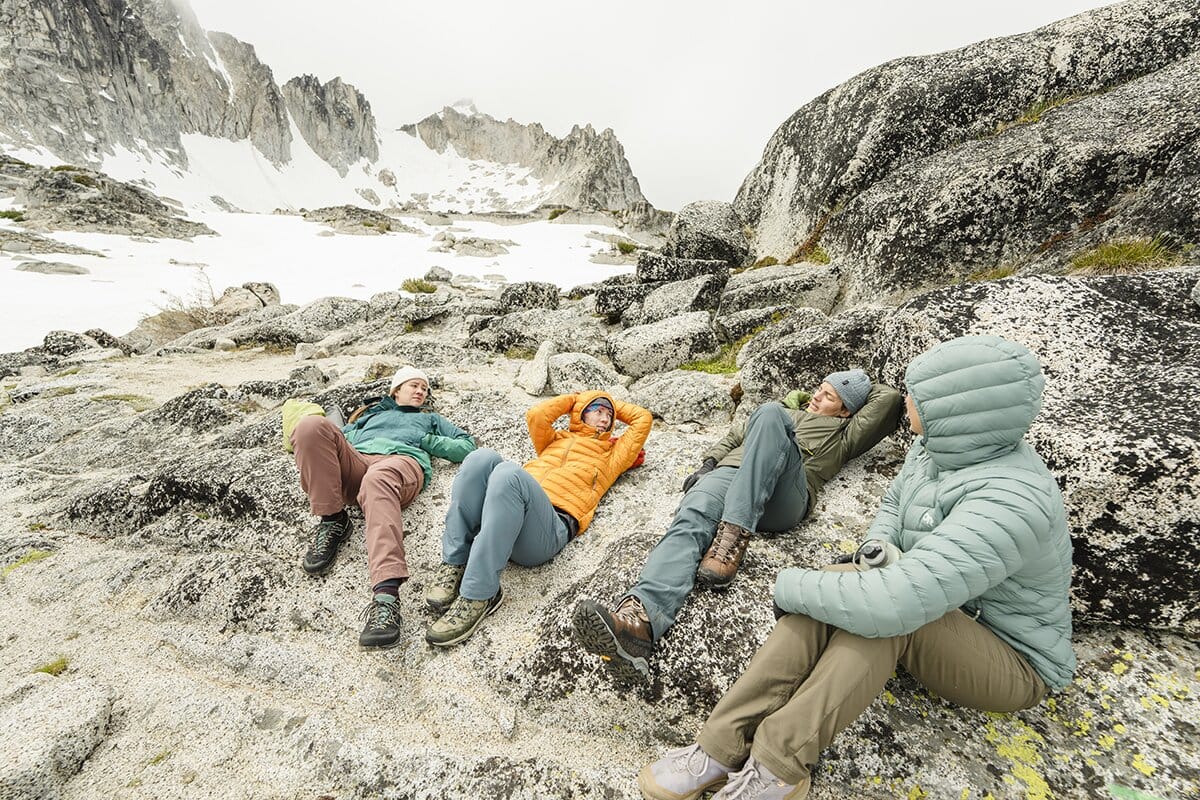 Four ladies lounging in the mountains wearing down and synthetic insulated jackets mobile
