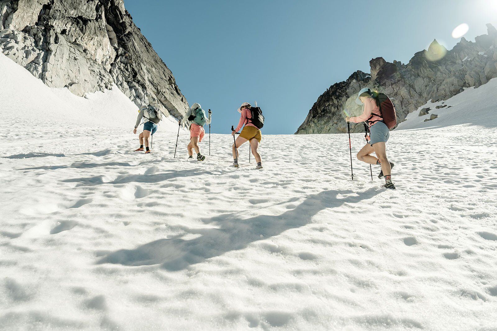 Four women hiking up glacier with trekking poles