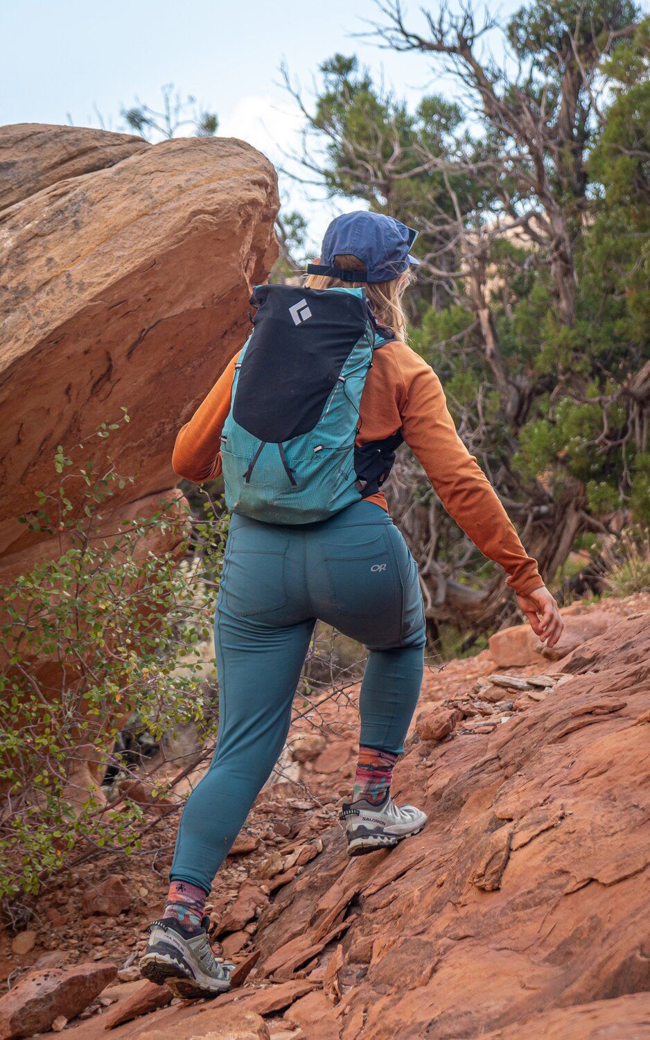 Hiker climbing over red rock wearing the Black Diamond Distance 22 hiking daypack