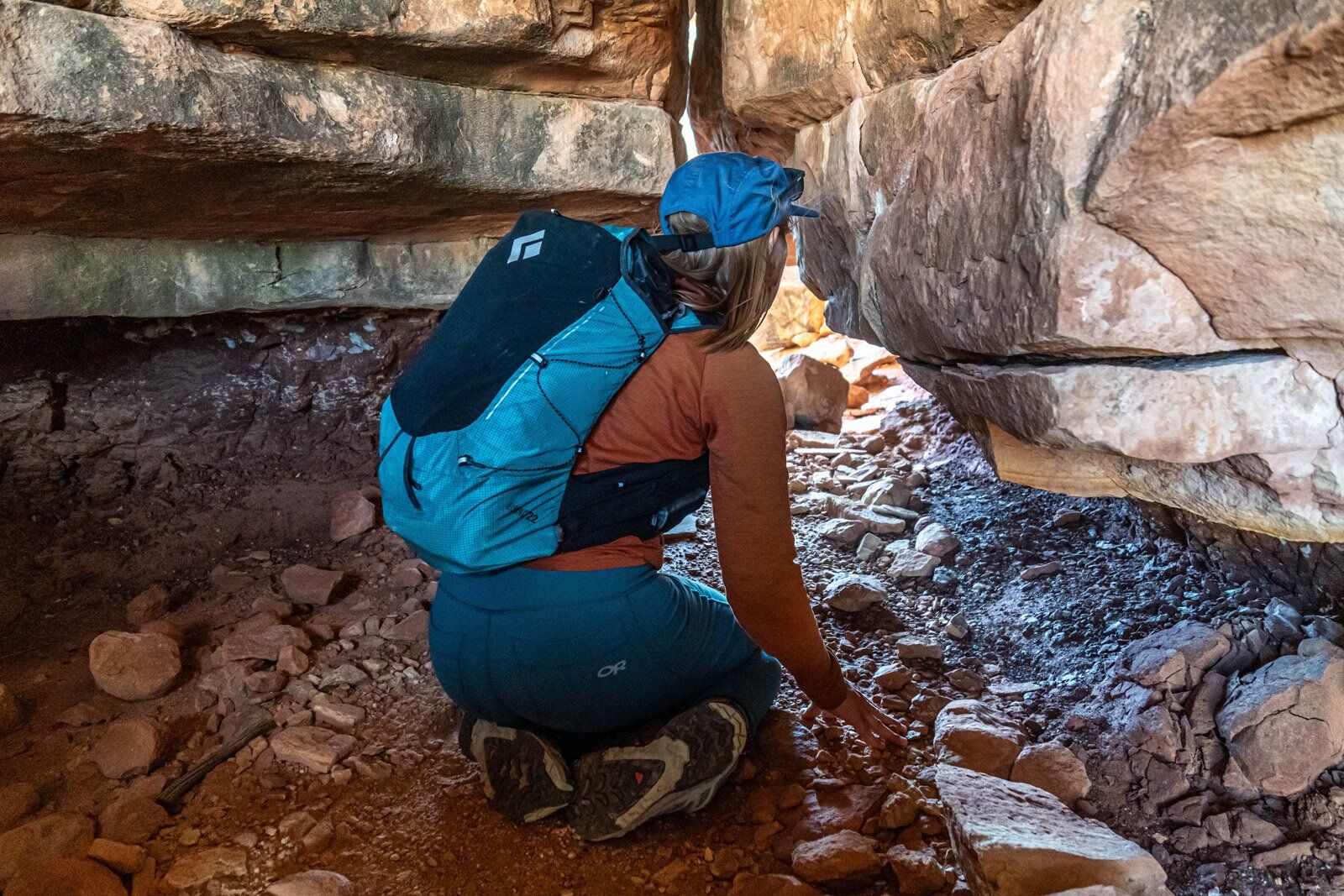 Hiker crouching in narrow canyon with Black Diamond Distance 22 hiking daypack