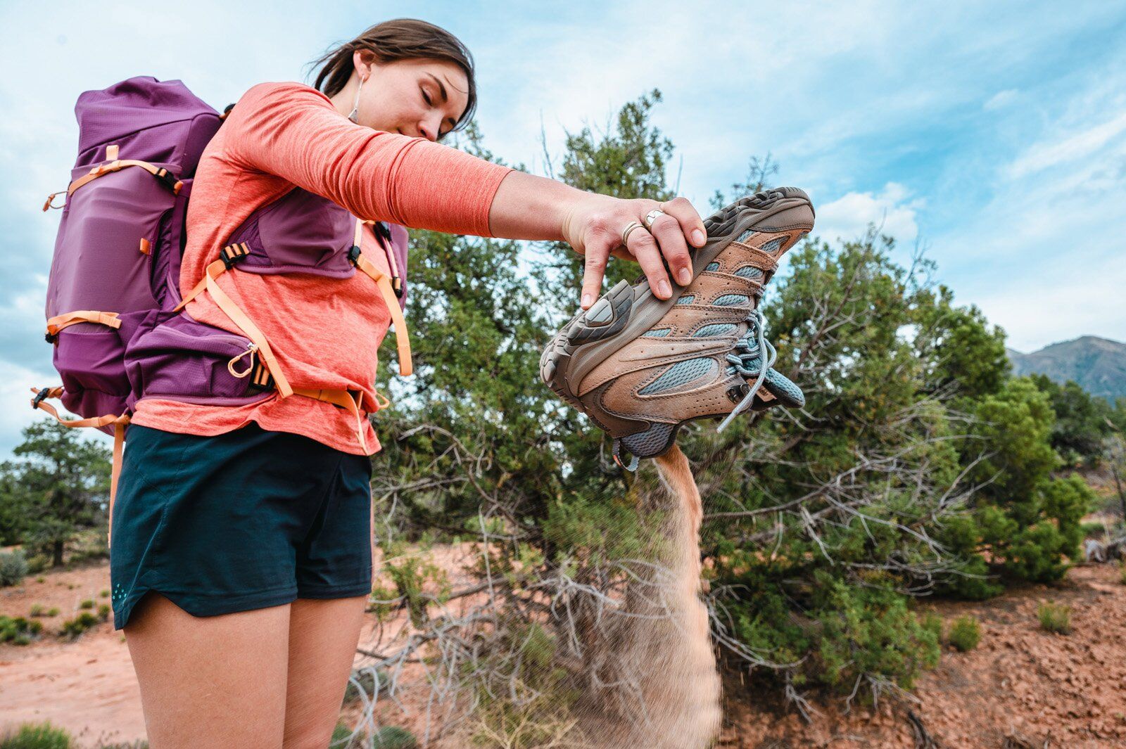 Hiker dumping out sand from boot wearing the Osprey Tempest Velocity 30 hiking daypack