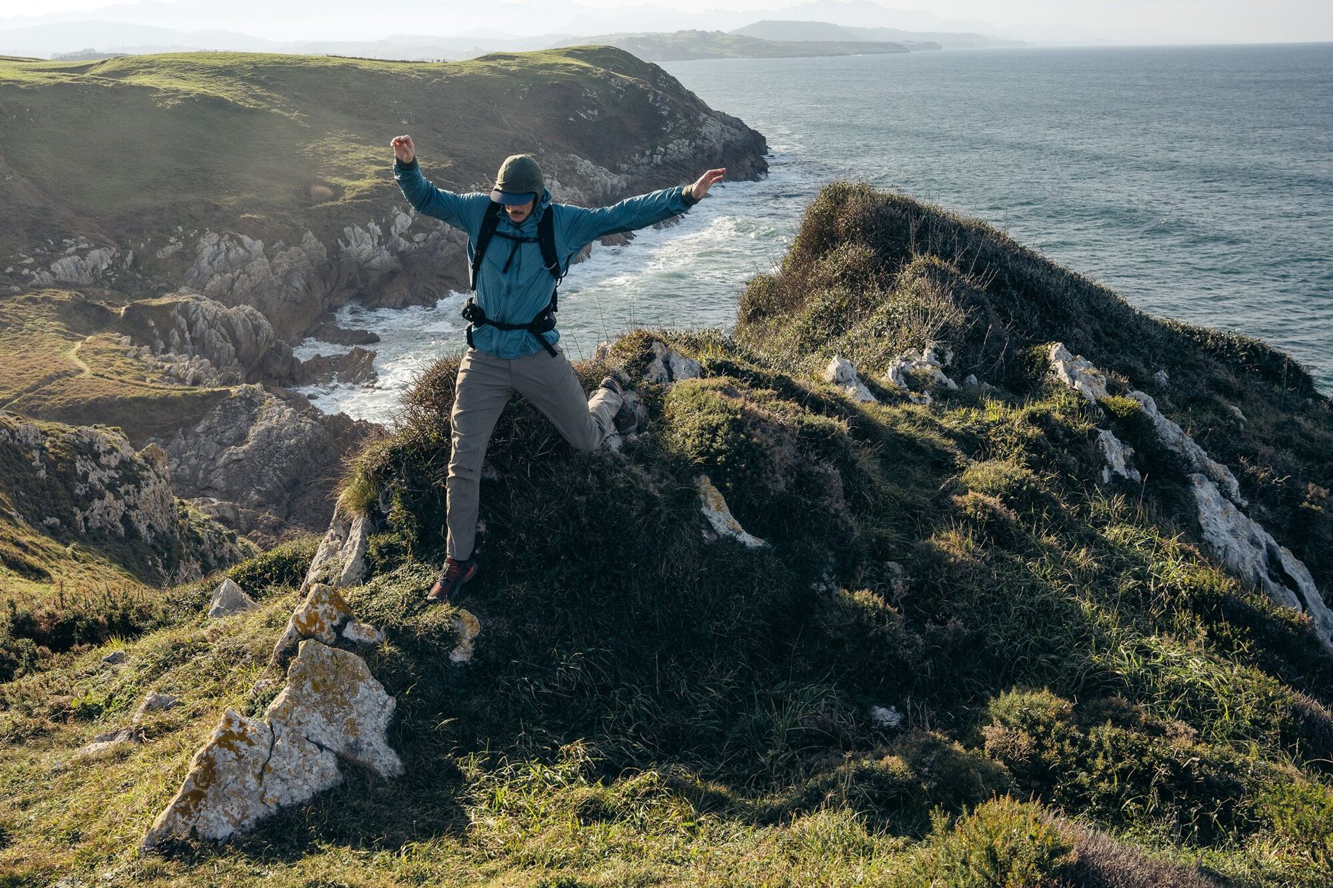 Hiker jumping off rocks wearing the Osprey Talon 22 hiking daypack