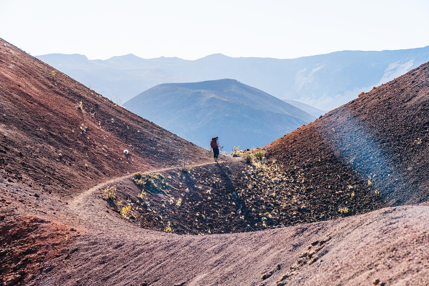 Hiker on dusty volcanic trail