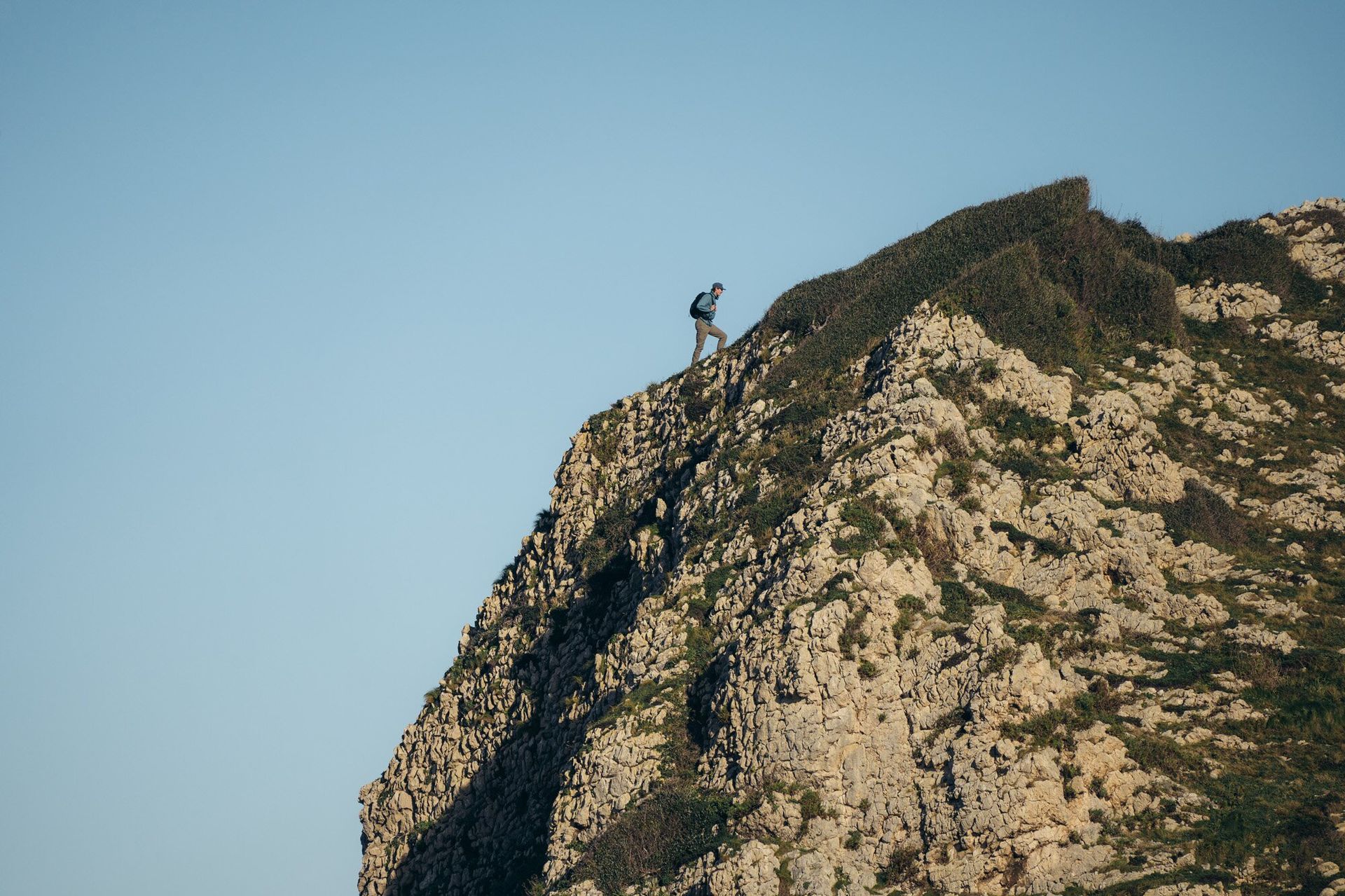 Hiker on the edge of a cliff wearing the Osprey Talon 22 hiking daypack