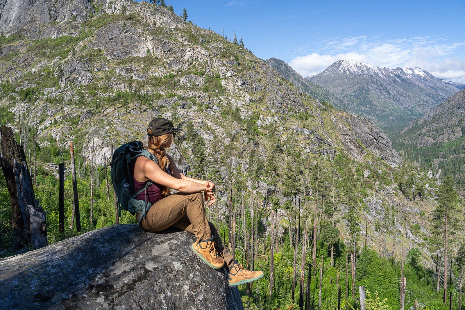 Hiker resting on boulder wearing the Osprey Mira 22 hiking daypack