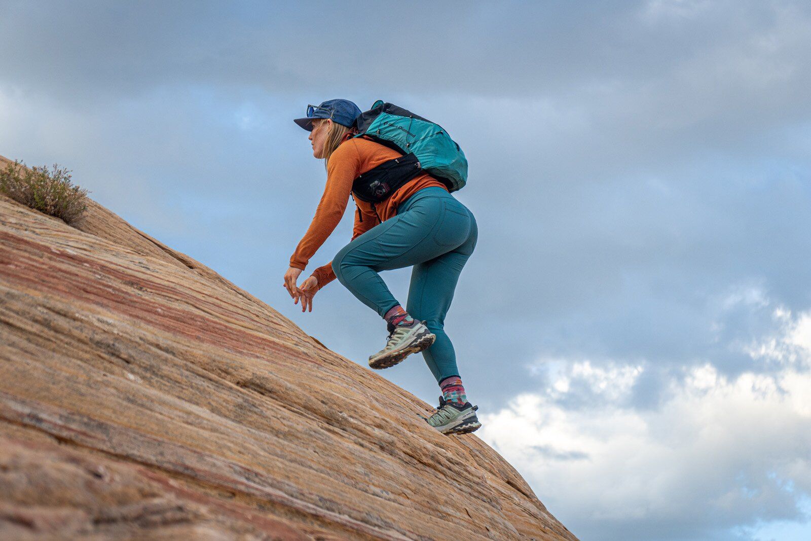 Hiker scaling rock slab with Black Diamond Distance 22 hiking daypack