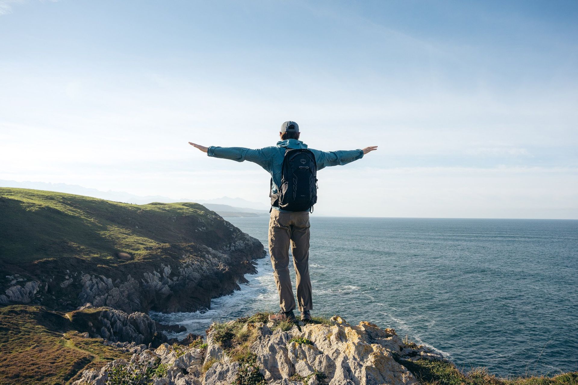 Hiker standing on cliff edge wearing Osprey Talon 22 hiking daypack.