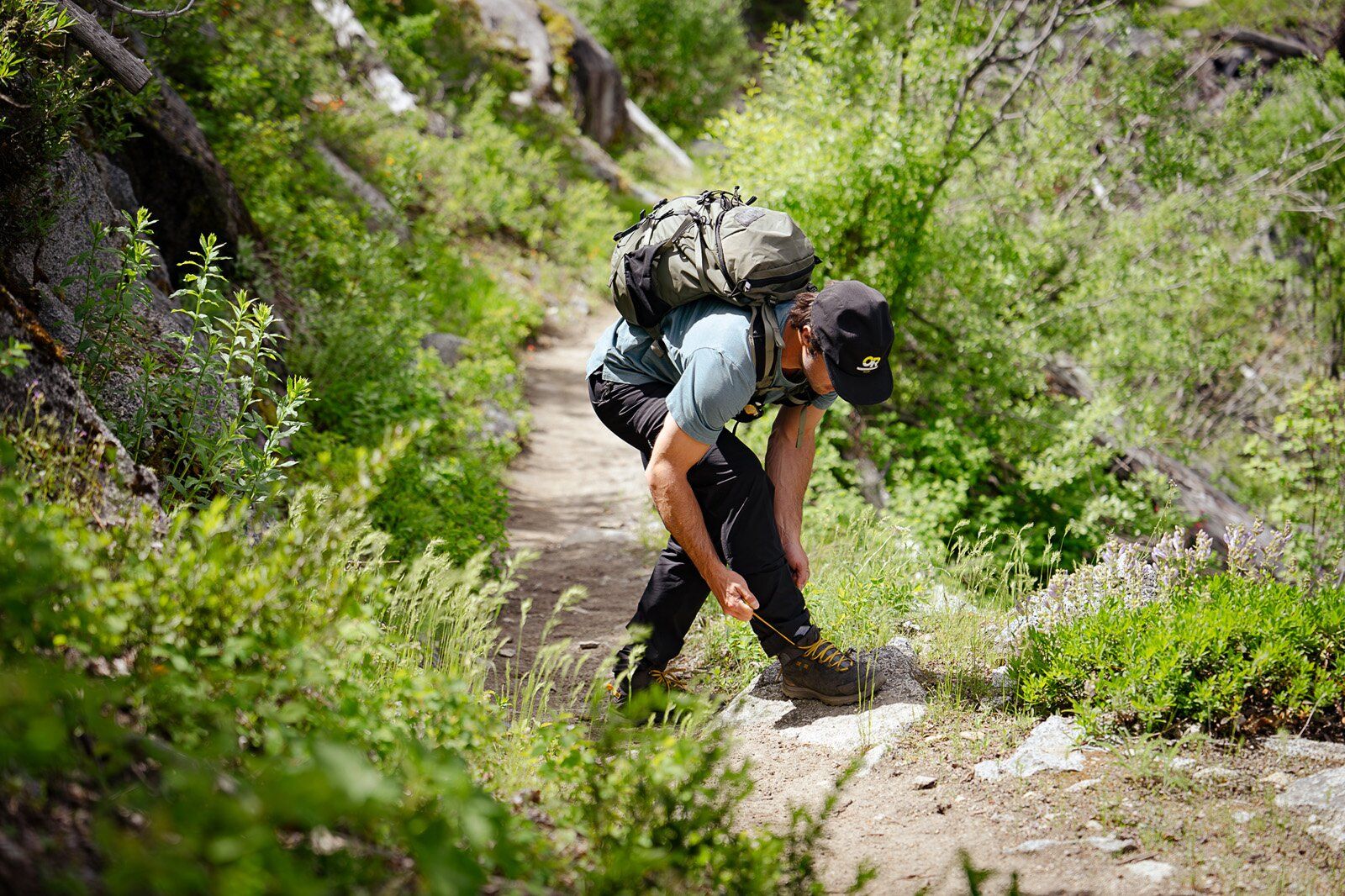 Hiker tying shoe wearing the Mystery Ranch Gallagator 25 hiking daypack