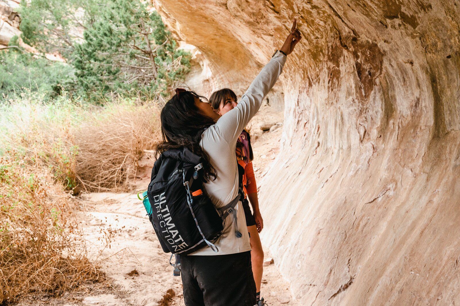 Hiker under rock overhang wearing the Ultimate Direction Fastpack 20 hiking daypack