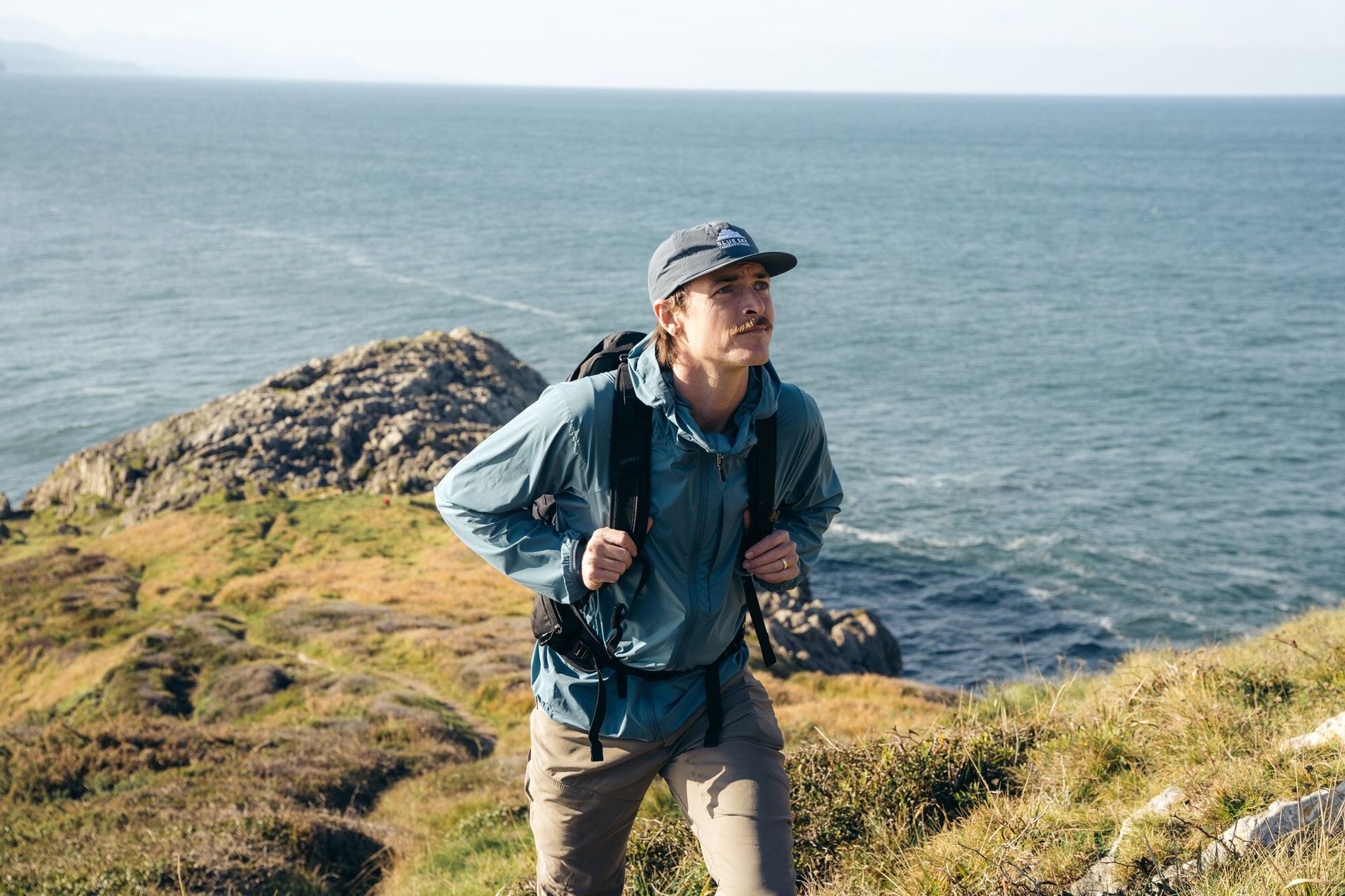 Hiking up a hill on the coast wearing the Osprey Talon 22 hiking