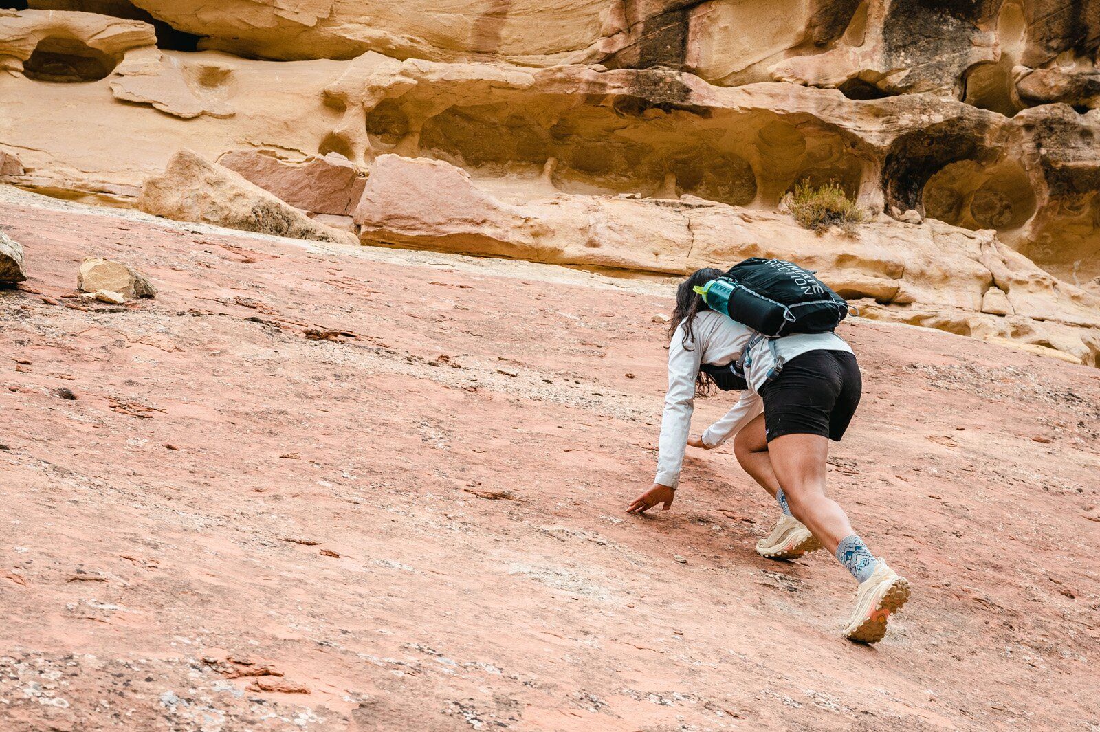 Hiking up rock slab wearing Ultimate Direction Fastpack 20 hiking daypack
