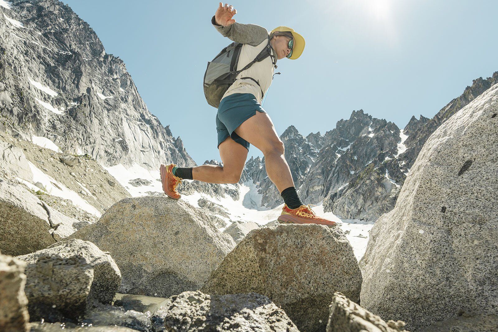 Jumping across stream wearing Deuter Speed Lite 21 backpack