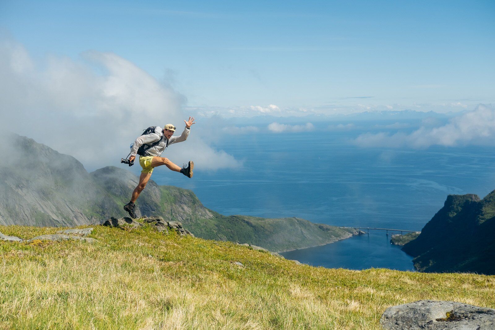 Jumping in mountain field with Osprey Stratos 34 hiking daypack
