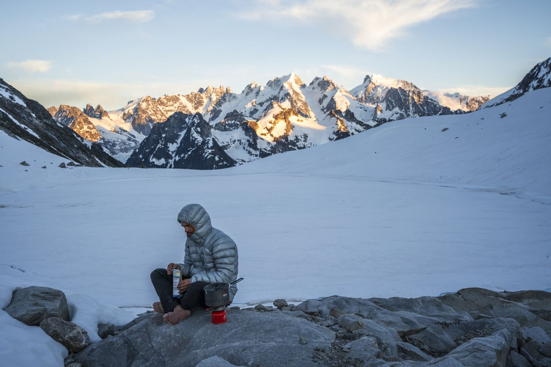 Man weaing Rab Mythic G down jacket with Waddington range in background