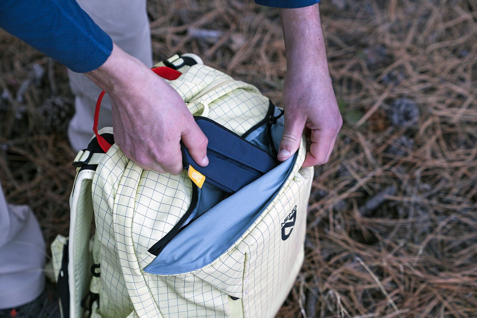 Putting sunglasses into zippered accessory pocket of Nemo Resolve Endless Promise 25 daypack