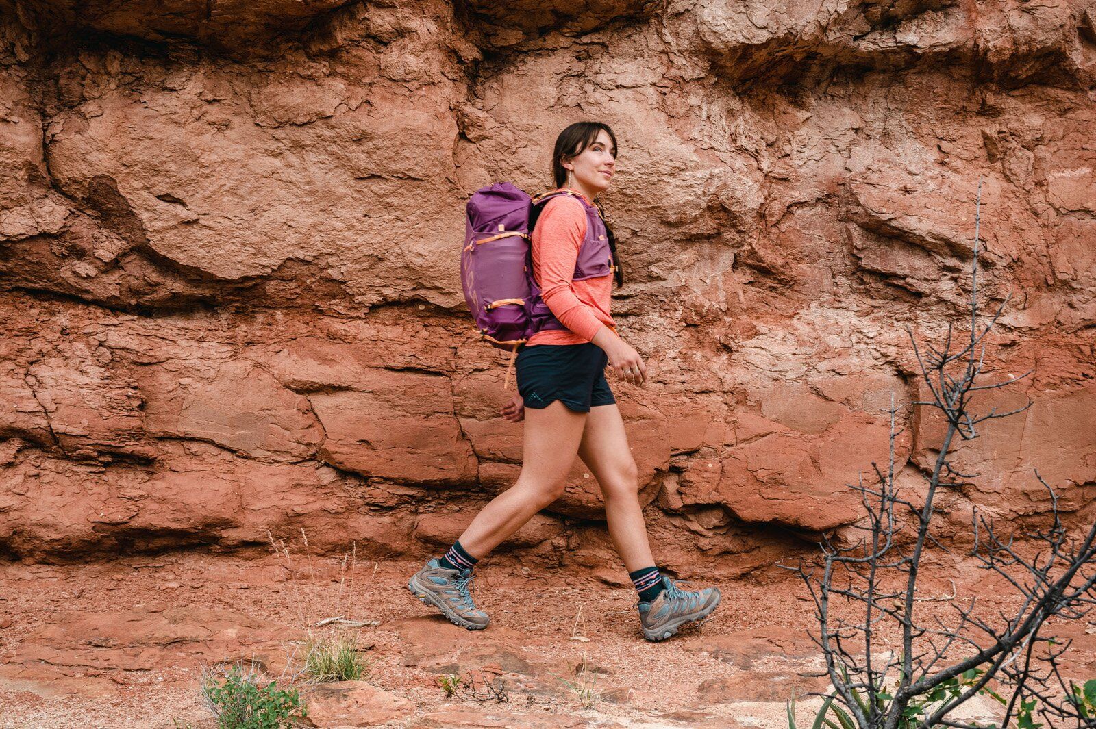 Red rock wall behind hiker with Osprey Tempest Velocity 30 hiking daypack