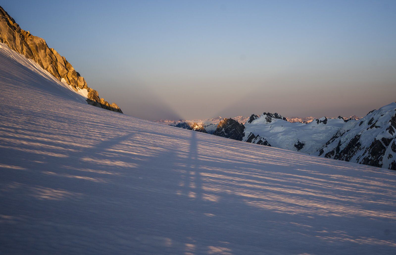 Shadow of man across glacier at sunset in mountains