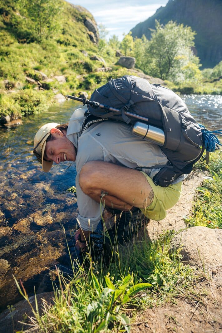 Side view of Osprey Stratos 34 hiking daypack with water bottle in mesh sleeve