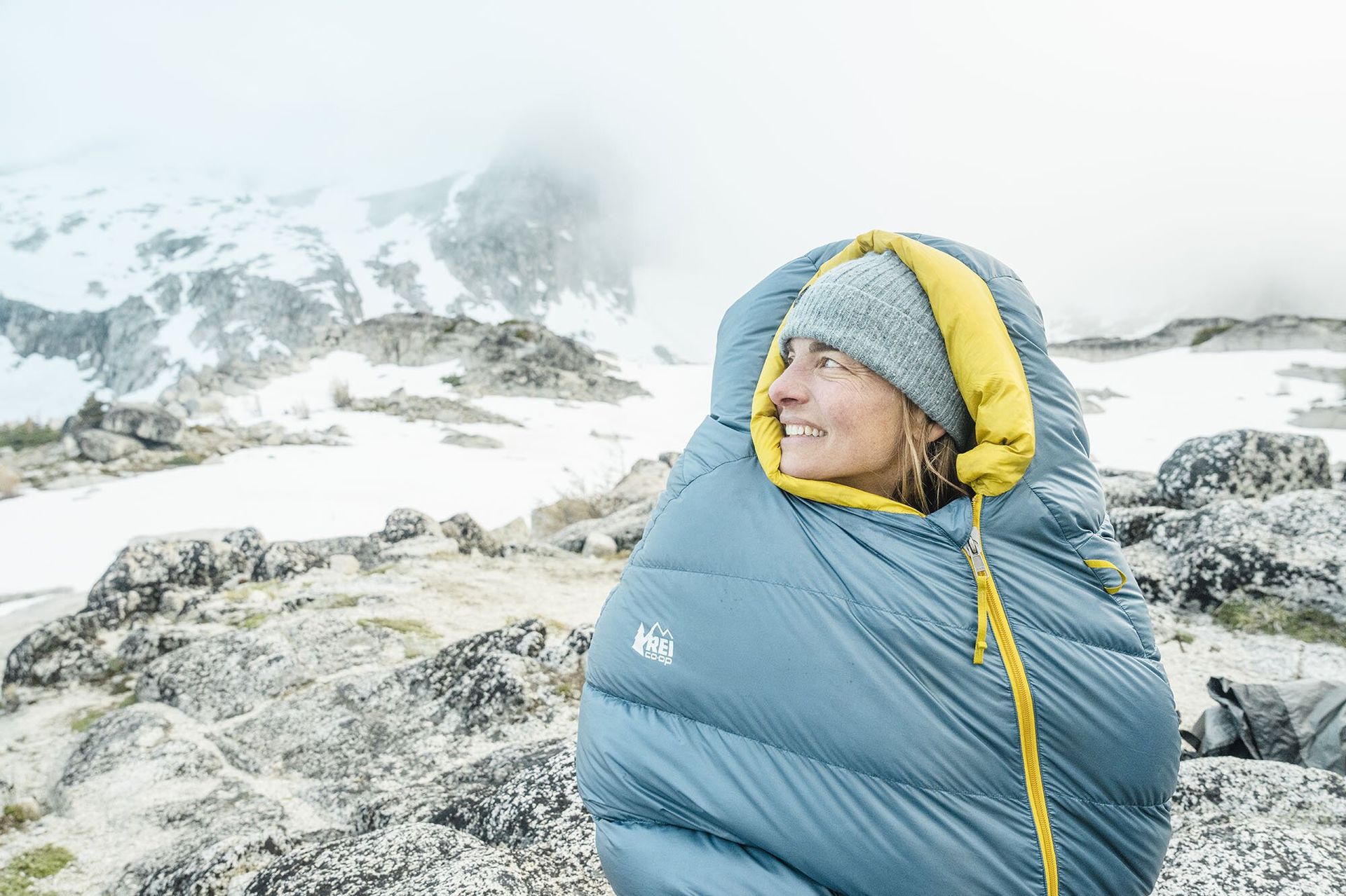 Smiling and sitting in REI Co-op Magma 30 sleeping bag