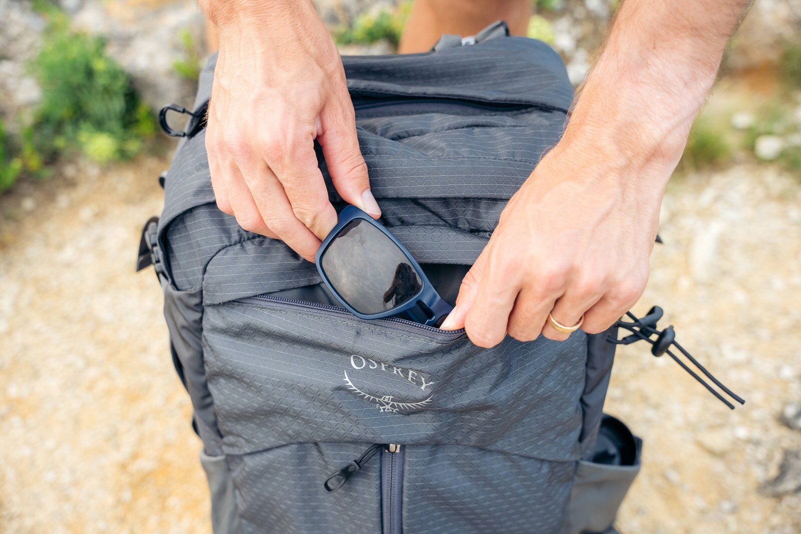 Sunglasses in zippered pocket on front panel of Osprey Stratos 34 hiking daypack