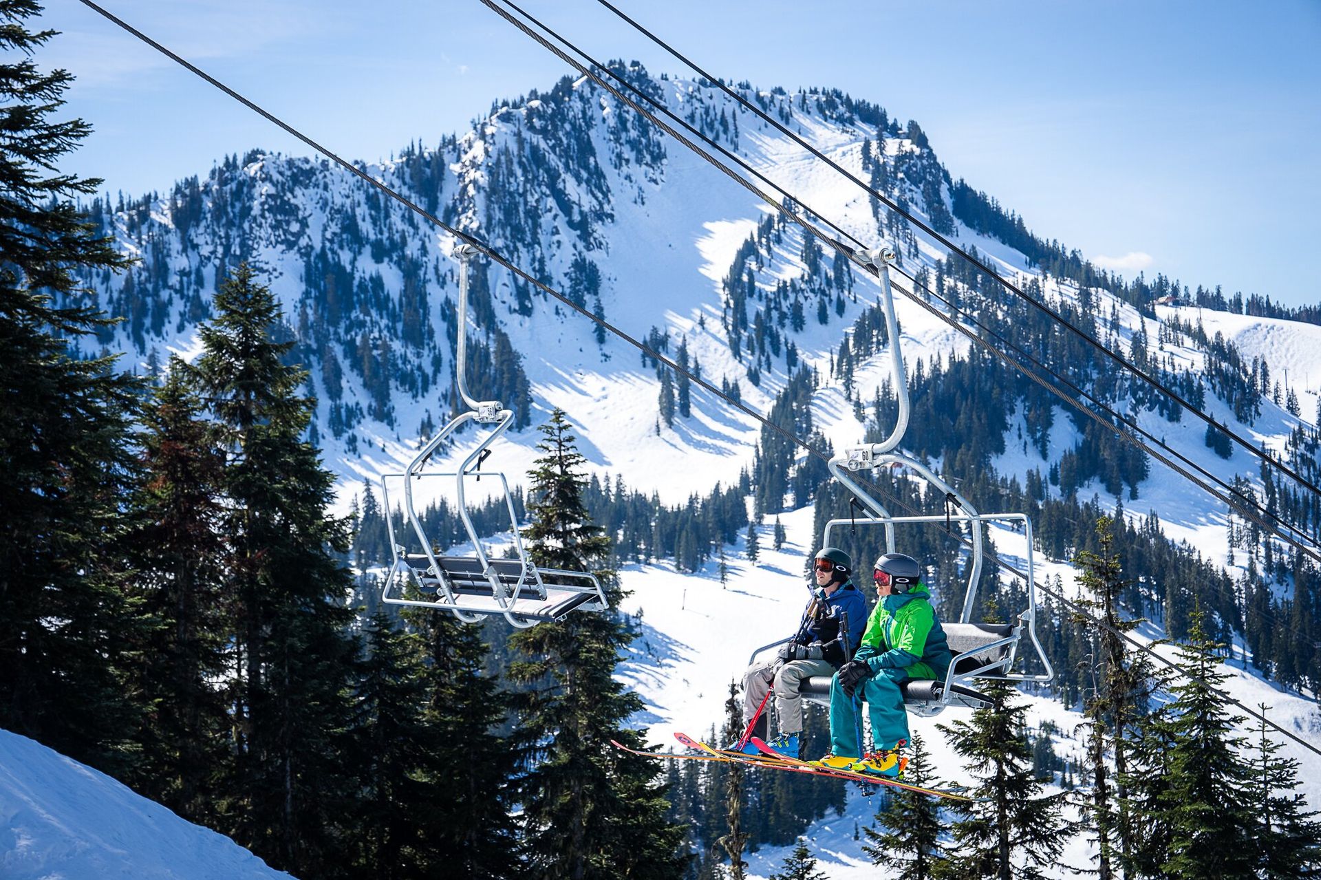 Two skiers riding a chairlift with Oakley ski goggles