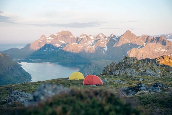 Two tents pitched on hillside overlooking fjord