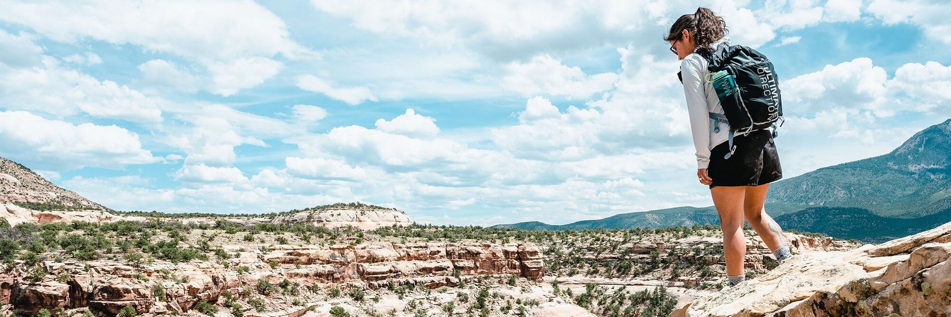 Woman looking into desert canyon wearing Ultimate Direction Fastpackher 20 daypack 3_1