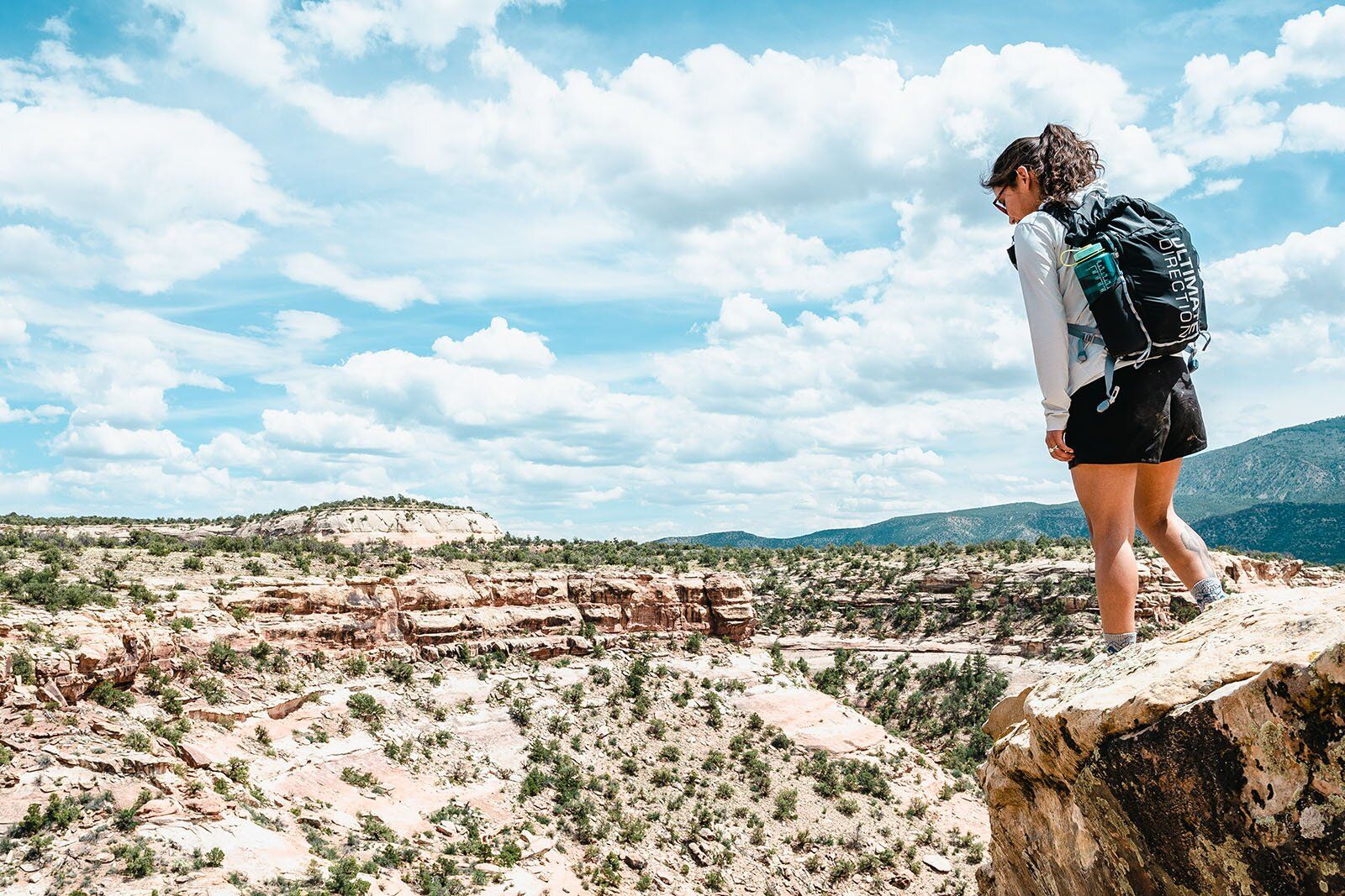 Woman looking into desert canyon wearing Ultimate Direction Fastpackher 20 daypack